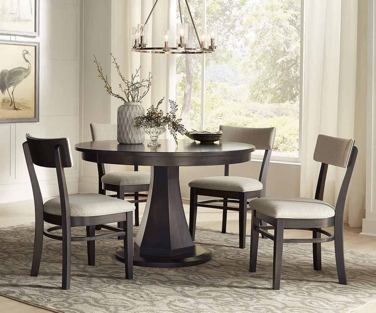 Round pedestal dining room furniture set with upholstered chairs in bright dining area