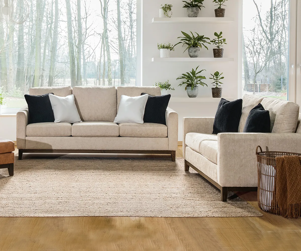 Cream upholstered living room furniture with sofas and black accent pillows in bright room