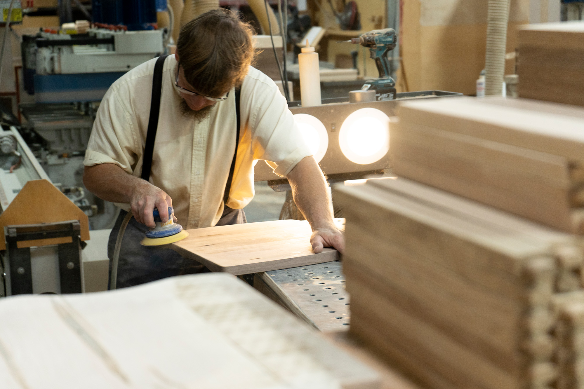 Handcrafted solid wood furniture panel being sanded in an Amish woodworking shop